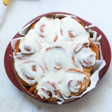 Sourdough Cinnamon Rolls in round pan topped with icing.
