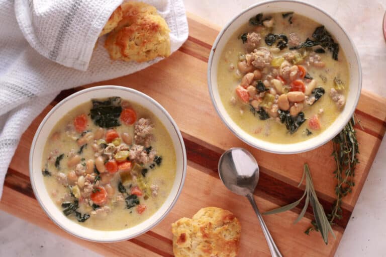 Tuscan white bean soup with biscuits on a cutting board.